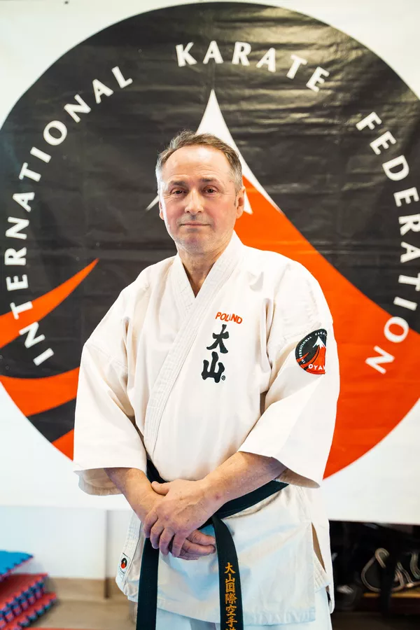 Witold Choiński na tle logo Oyama Polskiej Federacji Karate w dojo w Białymstoku